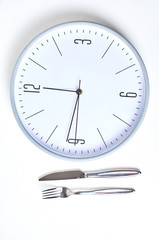 "Time to eat" concept. Clock, spoons, forks and knives.