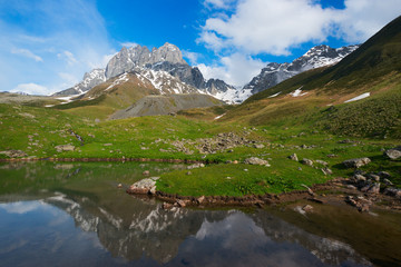 Naklejka na ściany i meble Mountain lake with reflection of high rocky peak
