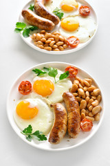 Fried eggs, sausages, beans, tomatoes and greens