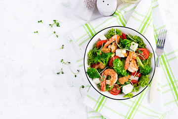 Delicious fresh salad with shrimps / prawns, broccoli, feta cheese, tomatoes, lettuce and peanut dressing. Diet menu. Top view, copy space