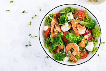 Delicious fresh salad with shrimps / prawns, broccoli, feta cheese, tomatoes, lettuce and peanut dressing. Diet menu. Top view, copy space
