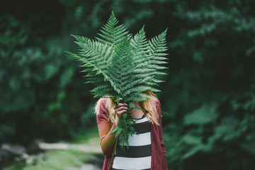 Young creative  girl holding green fern in the forest