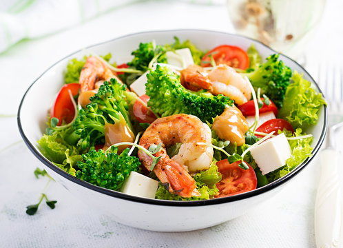 Delicious fresh salad with shrimps / prawns, broccoli, feta cheese, tomatoes, lettuce and peanut dressing. Diet menu. Top view