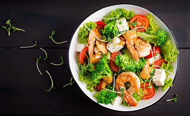 Delicious fresh salad with shrimps / prawns, broccoli, feta cheese, tomatoes, lettuce and peanut dressing. Diet menu. Top view, copy space