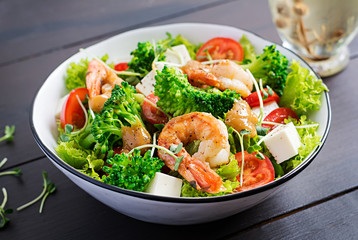 Delicious fresh salad with shrimps / prawns, broccoli, feta cheese, tomatoes, lettuce and peanut dressing. Diet menu.