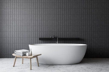 Fototapeta na wymiar Gray tile bathroom with white tub and chair