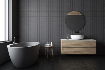 Luxury gray tile bathroom, tub and round mirror