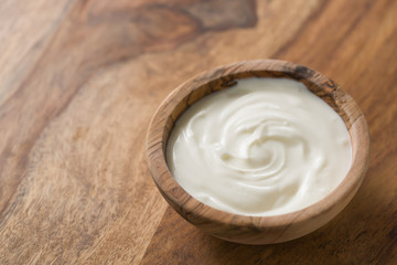 Obraz na płótnie Canvas organic white yogurt in olive wood bowl on table