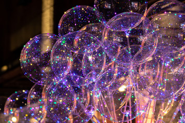 Leuchtende bunte transparente funkelnde Luftballons auf einem Weihnachtsmarkt oder einer Kirmes...
