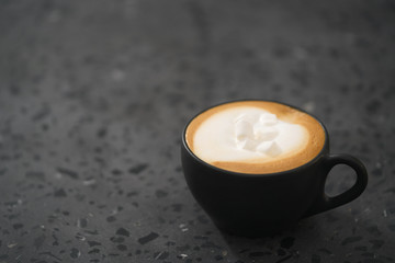 cappuccino with marshmallow in black cup on terrazzo surface with copy space