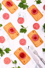 Crunchy crackers with salami and parsley on the table.