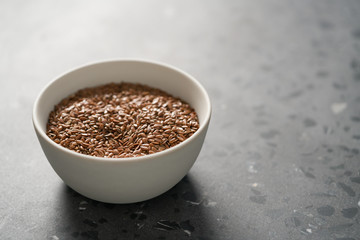 Flax seeds in white bowl on terrazzo surface with copy space