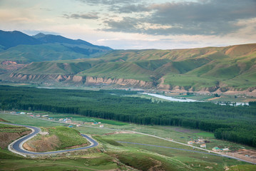 Landscape of village in mountain valley with rural road winding up