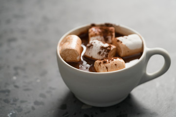 Cocoa drink with marshmallow in white cup on terrazzo surface with copy space