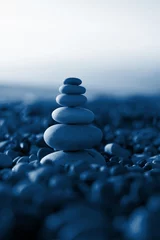 Pyramide aus Kieselsteinen am Strand Meer. von der Sonne beleuchtet. klassisches blaues Pantone 2020. Hintergrundbild. Platz für Text © Taranova_ksenya