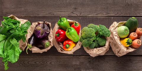 Set of fresh vegetables in different eco bags on wood