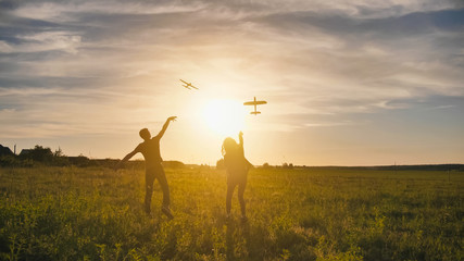 A guy and a girl launch a paralon plane at sunset.