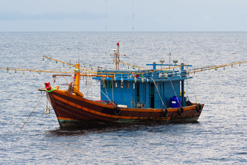 Fishing boats are overwhelmingly in the midst of the sea on a beautiful blue sky.