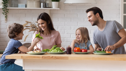 Couple with children sitting at kitchen countertop preparing healthy dinner