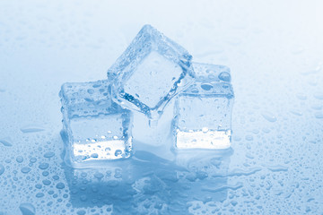Ice three cubes square with drops water clean on blue background