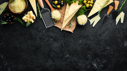 Set of hard cheeses with cheese knives on black stone background. Parmesan. Top view. Free space for your text. - obrazy, fototapety, plakaty