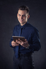 Handsome businessman using electronic tablet on the dark background