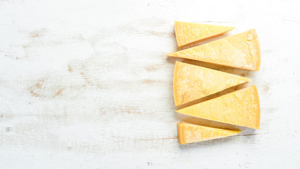 Piece of hard cheese on a white wooden background. Parmesan. Top view. Free space for your text.