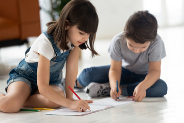 Brother and sister sitting on floor pencil drawing on paper.