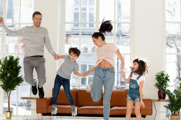 Happy family with two children jumping at home.