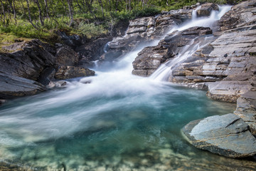 Waterfall landscape with flowing river and rock at sunny summer day in Abisko, Sweden. Silverfallet.