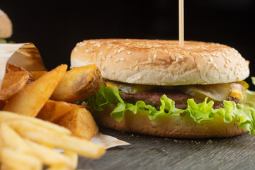 cheeseburger with beef patty with french fries and ketchup on a black background