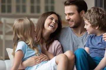 Obraz premium Happy couple holding on lap kids laughing enjoy time together
