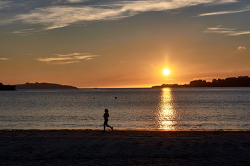 Fototapeta premium Sunset at sea and runner in silhouette. Landscape at sunset