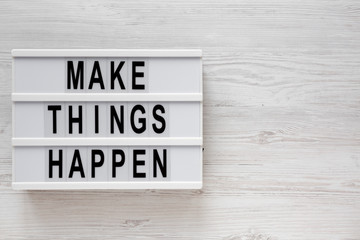 'Make things happen' words on a modern board on a white wooden surface, top view. Overhead, from above, flat lay. Space for text.