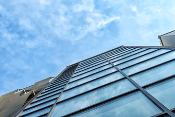Fototapeta na wymiar Modern mirror building on a background of cloudy sky. Bottom view Architecture.