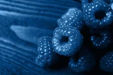 The color of the year 2020 is Classic blue. A handful of raspberries close up on a brown...
