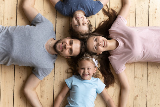 Above view couple and kids lying on wooden warm floor
