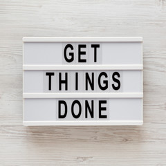'Get things done' words on a modern board on a white wooden background, top view. Overhead, from above, flat lay. Close-up.