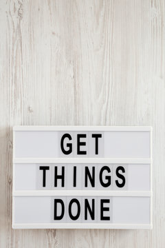 'Get things done' words on a lightbox on a white wooden background, top view. Overhead, from above, flat lay. Copy space.
