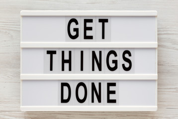 'Get things done' words on a lightbox on a white wooden background, top view. Overhead, from above, flat lay. Closeup.