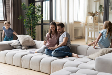 Fototapeta premium While parents resting with smartphone kids running at home