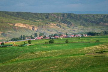 Fototapeta na wymiar Pastoral village in valley with farm field on foreground
