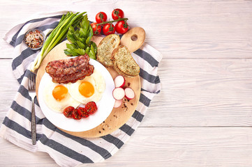 fried eggs on a wooden table, accompanied by fresh green parsley, cherry tomatoes on a branch, with fried crispy bacon and toasted baguette.