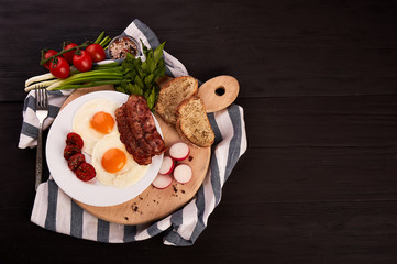 fried eggs on a wooden table, accompanied by fresh green parsley, cherry tomatoes on a branch, with fried crispy bacon and toasted baguette.