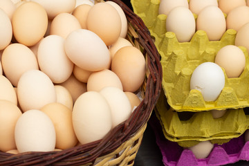 Fresh chicken eggs in a basket and in a cardboard container close up, selective fokus.