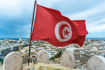 Closeup view of red Tunisian flag standing on roof of high building isolated at aerial view...