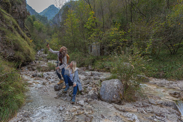 Couple of women making a selfie in a mountain stream of the Dolomiti Bellunesi National Park, Italy. Concept: photography, tourism, photos of people in a natural context, travel photos
