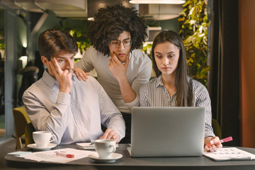 Upset business team analyzing financial data on laptop
