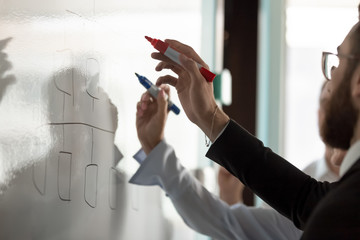 Businesspeople write on white board developing business plan together - obrazy, fototapety, plakaty