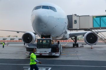 Closeup high detailed view of refueling operation of large widebody passenger aircraft standing on airport's parking place at ground maintenance. Dubai morning dawn